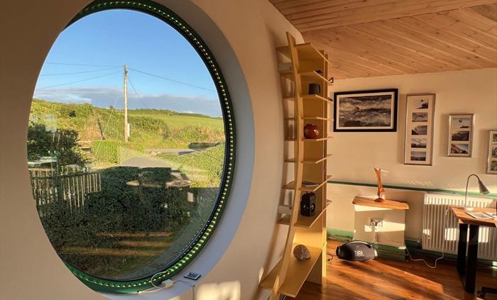 A porthole window in an accommodation looking out toward the countryside.